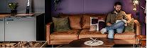 Cozy Lounge at Capsule Hotel, featuring a guest relaxing on a brown leather sofa with elegant decor and ambient lighting.