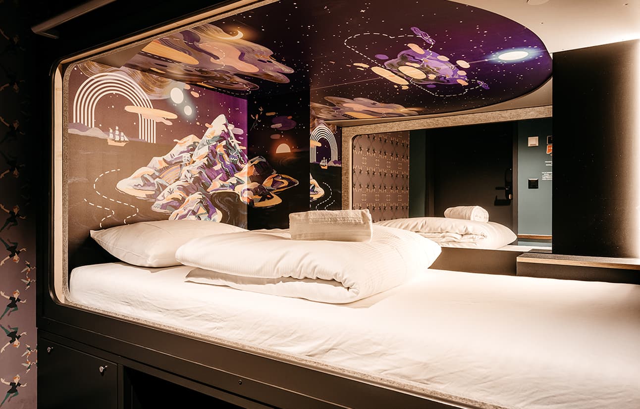 Capsule Hotel cozy capsule pod with galaxy mural, crisp white bedding, and towel in a modern shared room