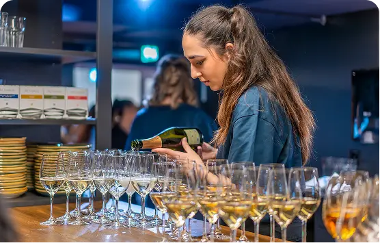 Capsule Hotel bartender pouring sparkling wine into rows of glasses at the bar
