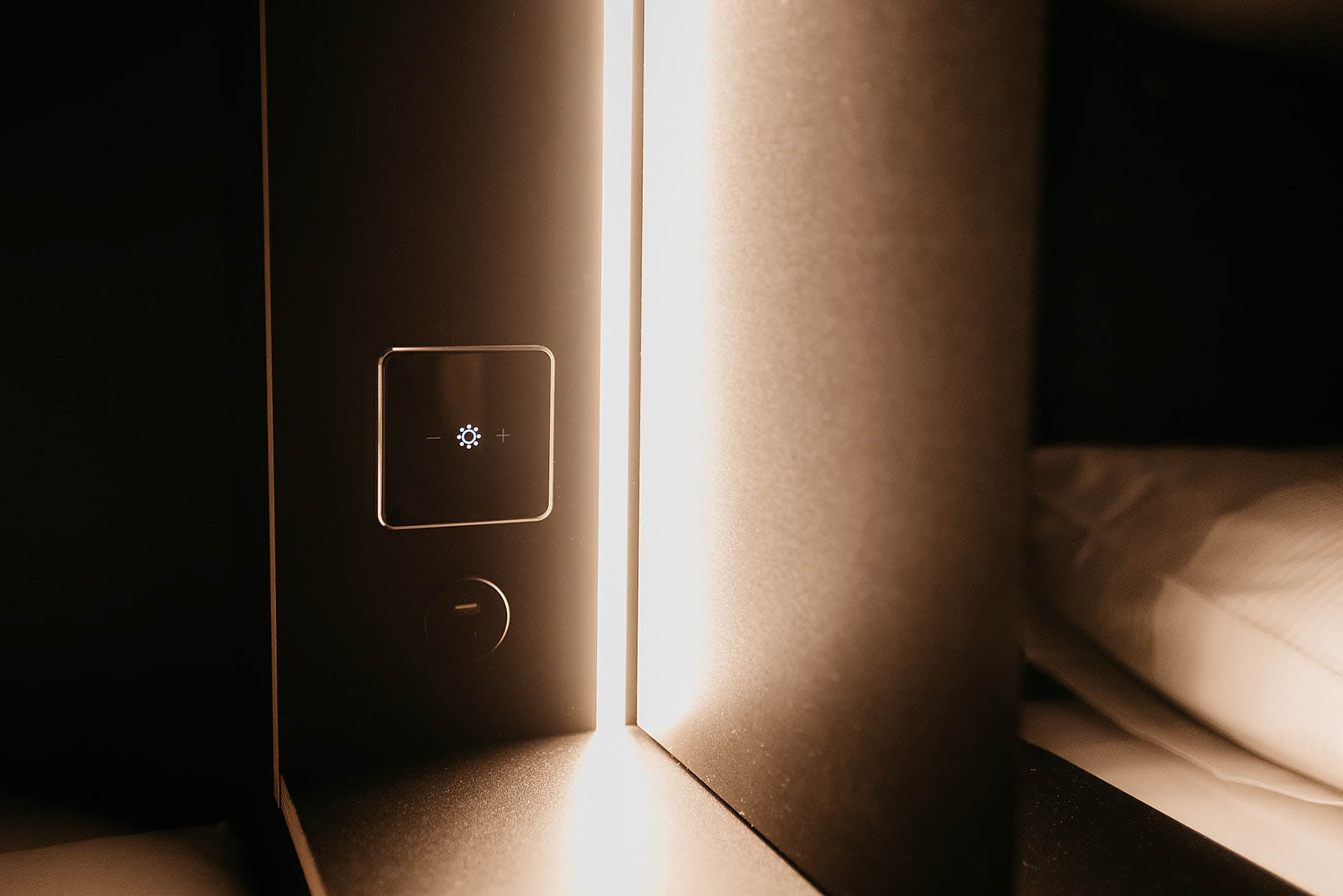 Soft-lit bedside control panel inside a capsule room at Capsule Hotel Lucerne Old Town.