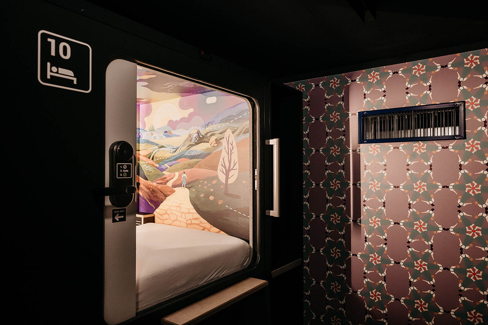 Colorful capsule room with scenic mural and modern design at Capsule Hotel Lucerne Old Town.