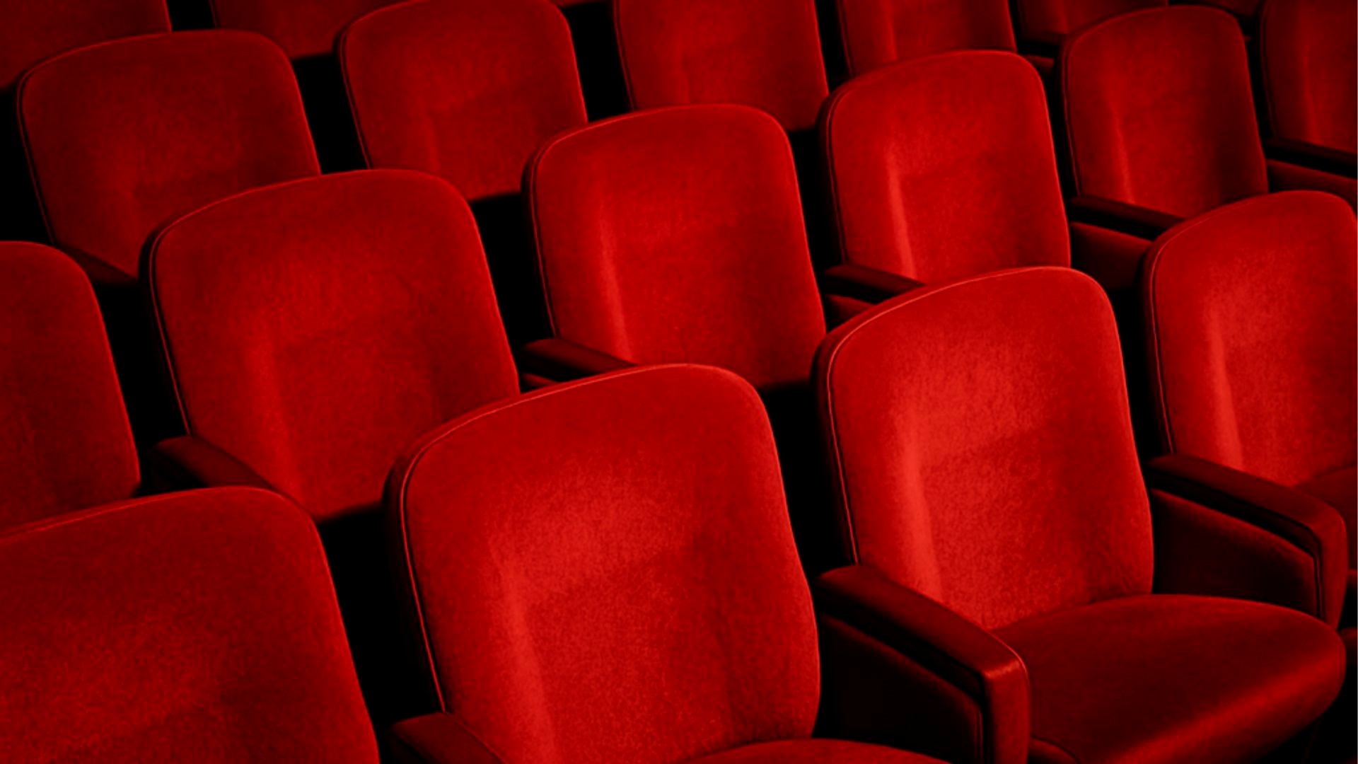 Capsule Hotel rows of plush red cinema seats with armrests in an empty theater