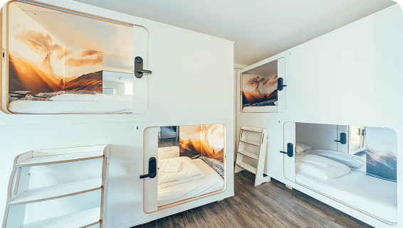 Capsule Hotel modern pod room with stacked white sleeping capsules, ladders, and mountain mural accents.