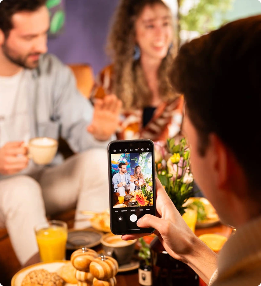 Breakfast spread with pastries and coffee as guests snap a smartphone photo in the Capsule Hotel lounge.