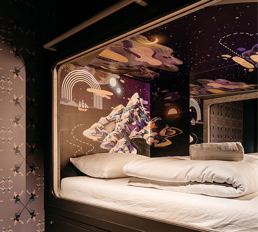Capsule Hotel pod with crisp white bedding and cosmic mountain mural, warm lighting and artistic walls.