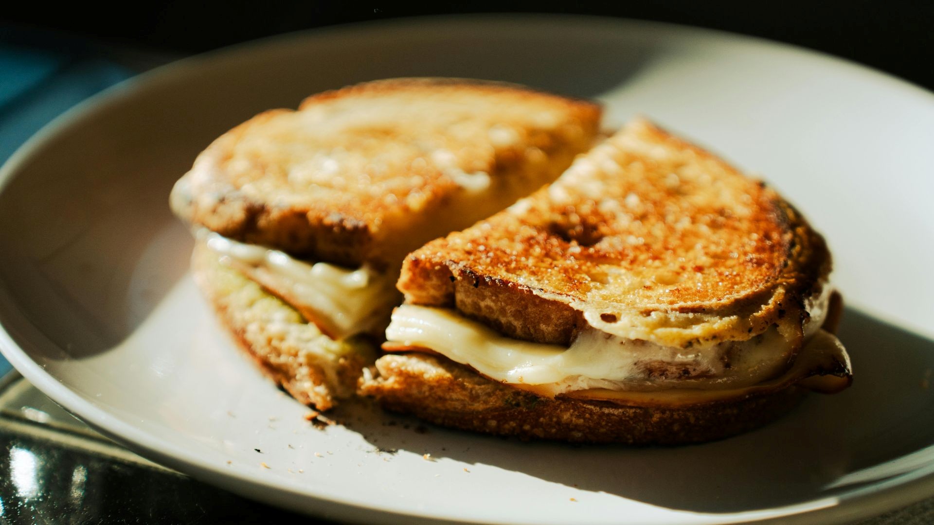 Toasted grilled cheese sandwich with melted layers on a white plate at Capsule Hotel.