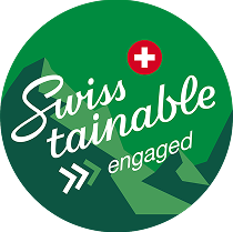 Capsule Hotel Swisstainable engaged badge with Swiss cross on green circle, sustainability commitment mark