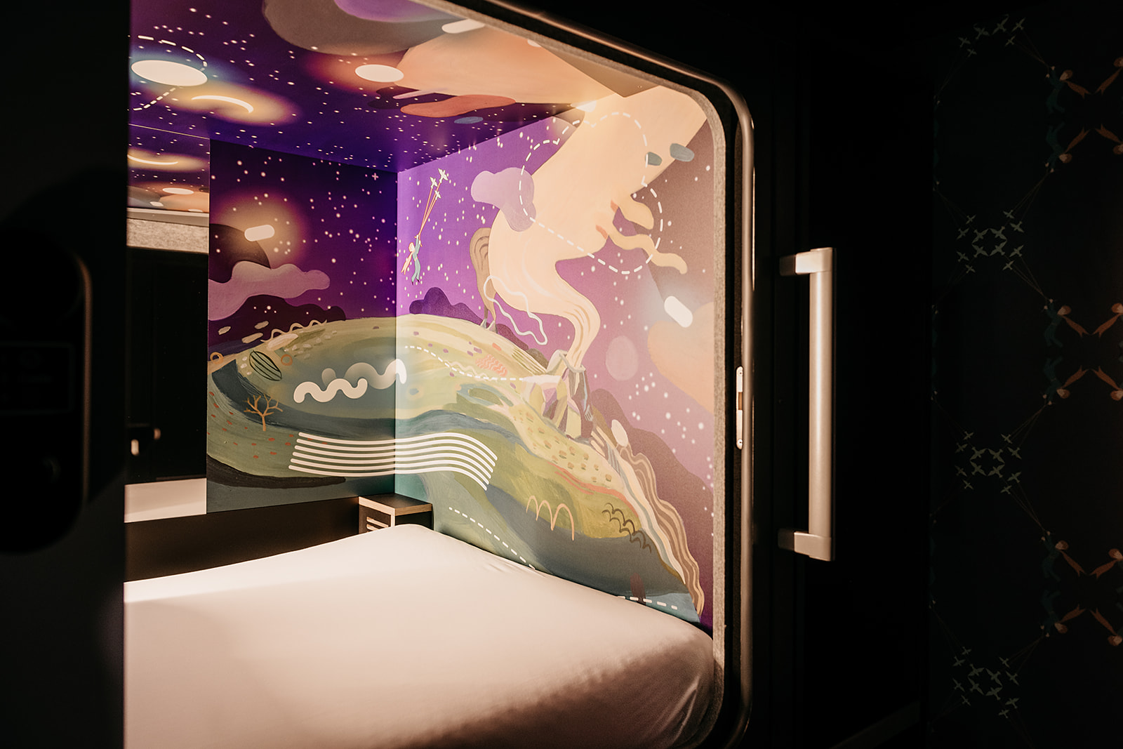 Artistic capsule interior with cosmic mural, highlighting a vibrant stay at Capsule Hotel.