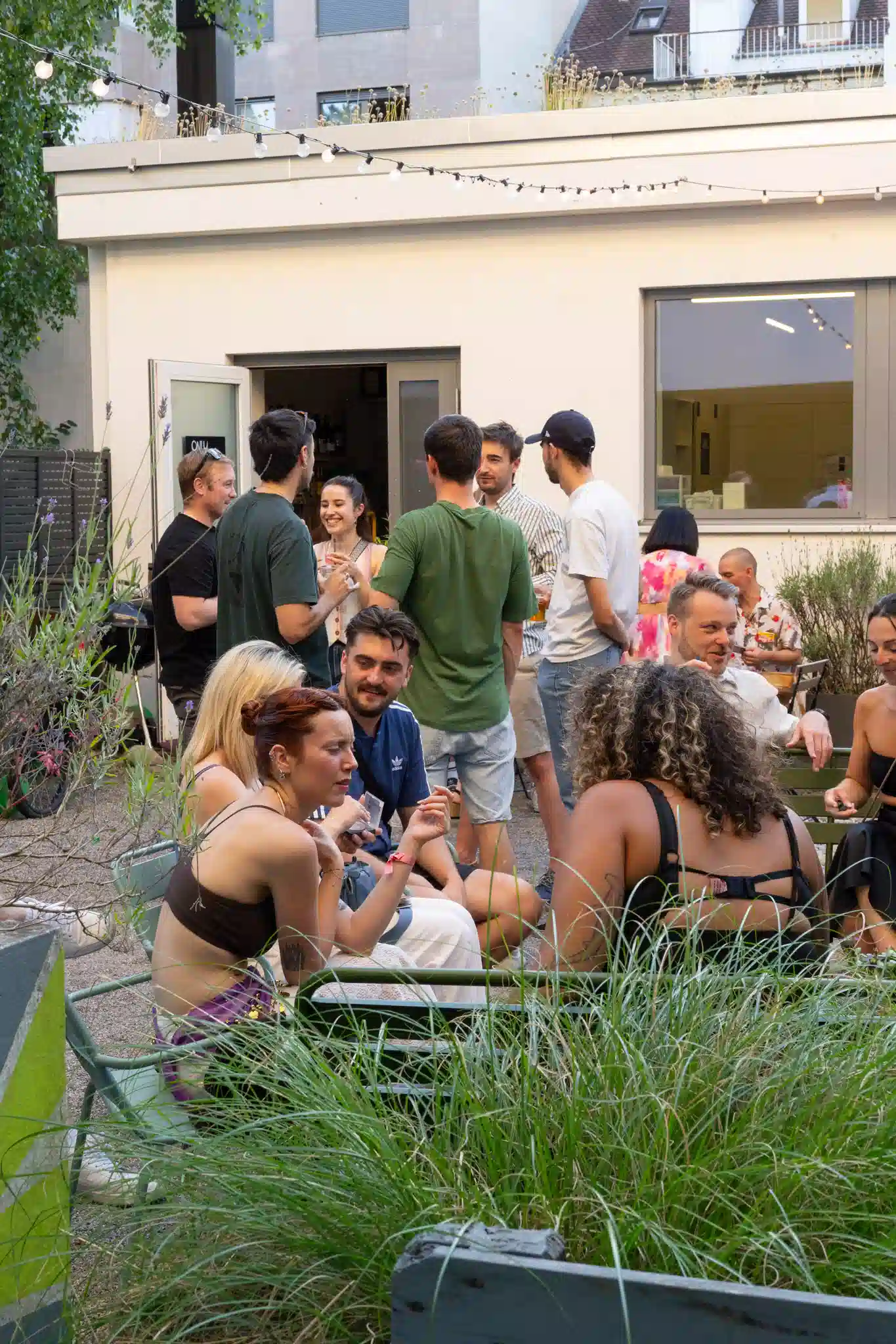 Gäste unterhalten sich im Gartenbereich des Hyve Basel Capsule Hotels.