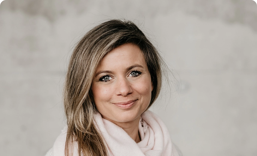 Capsule Hotel team portrait: smiling woman with long hair and pink scarf on neutral background