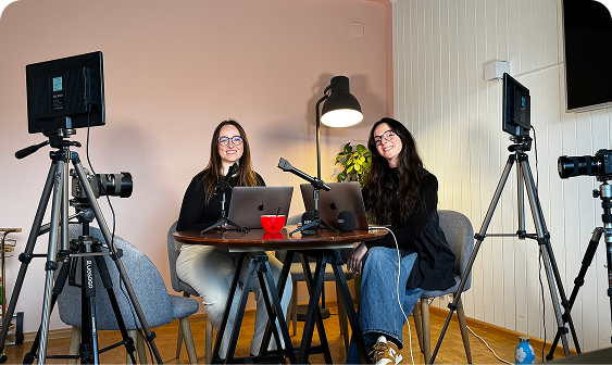 Two women sit at a round table with laptops in a stylish office setting for Capsule Hotel brand photography.
