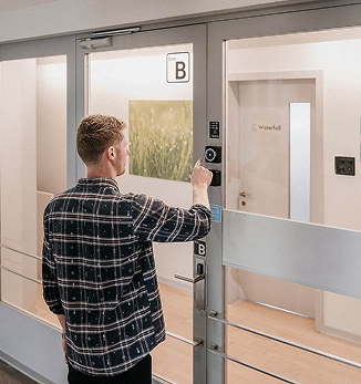 Accessing Capsule Hotel room using digital key entry system in modern hallway.