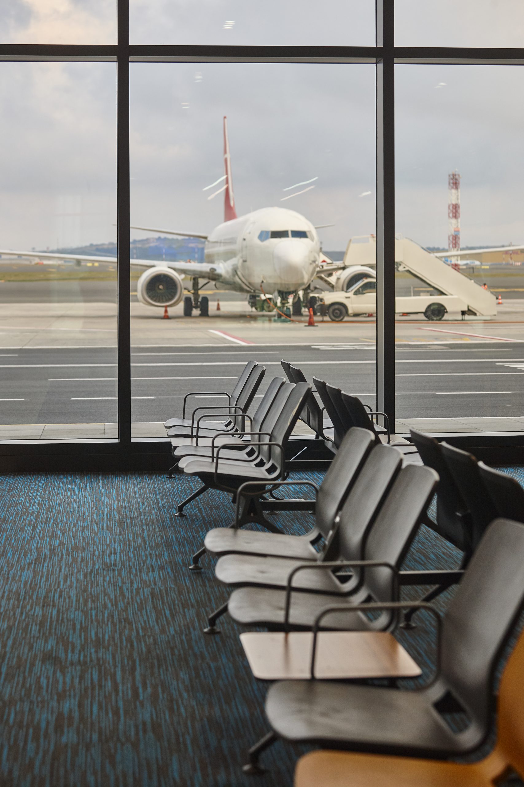 Sitzgelegenheiten in der Flughafen-Lounge des Capsule Hotels am Fenster mit einem geparkten Flugzeug am Gate.