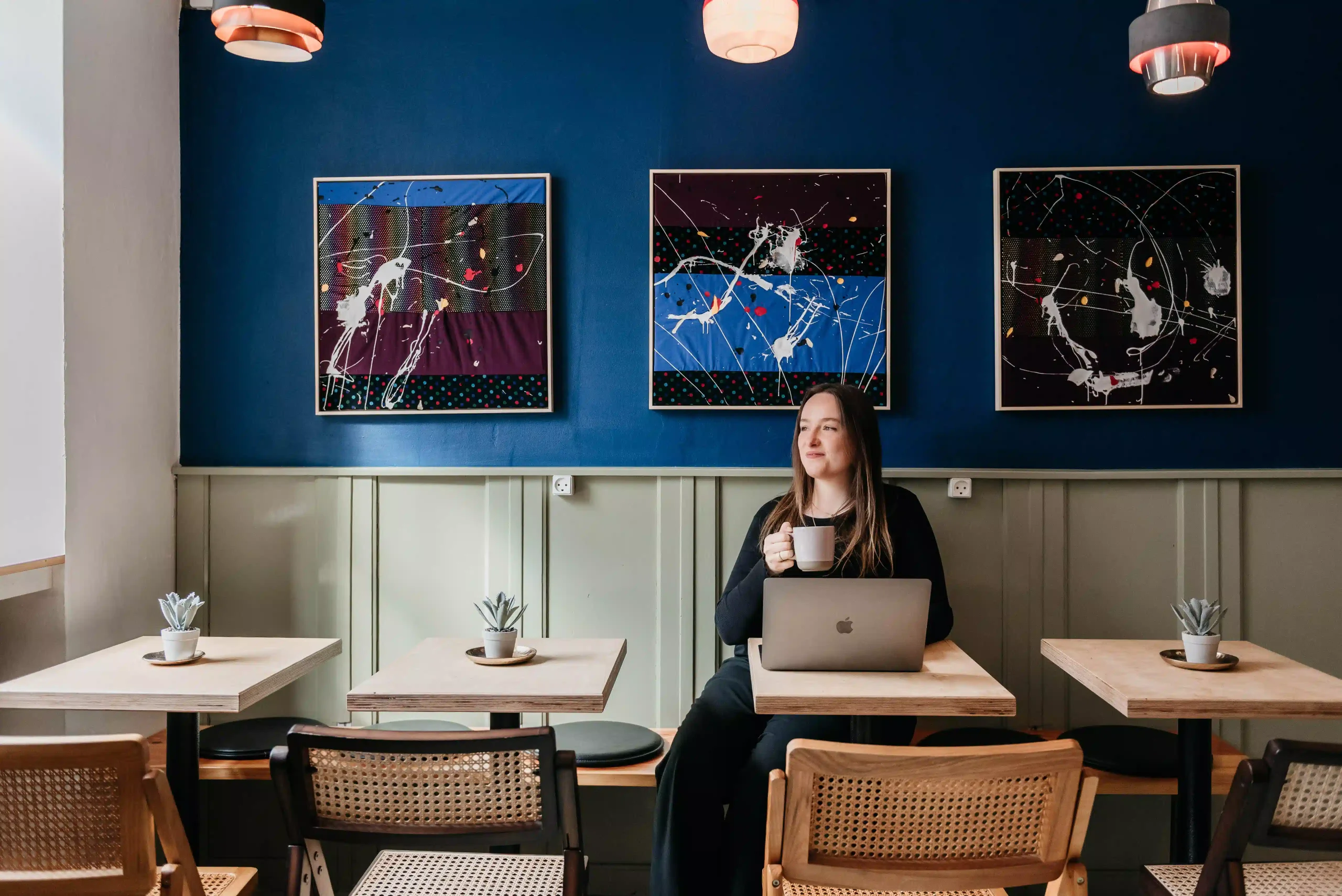 Seating area with modern art and a person enjoying coffee at Capsule Hotel Copenhagen Vesterbro.