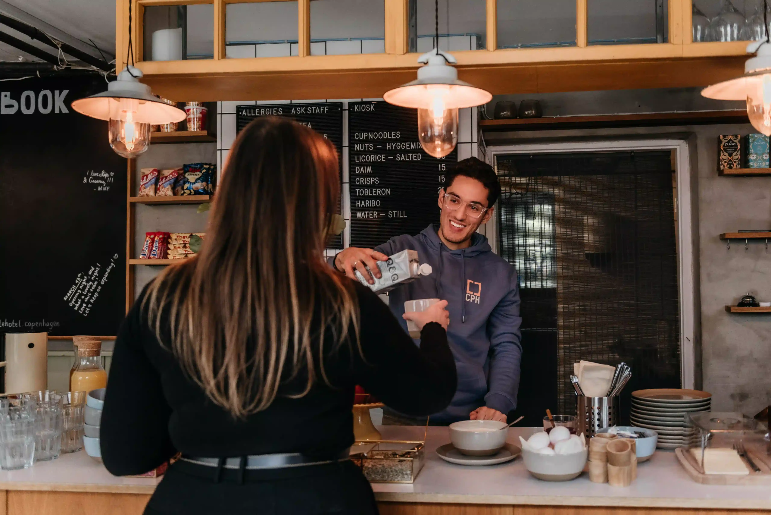 Barista pours drink for guest at Capsule Hotel Copenhagen Vesterbro café.
