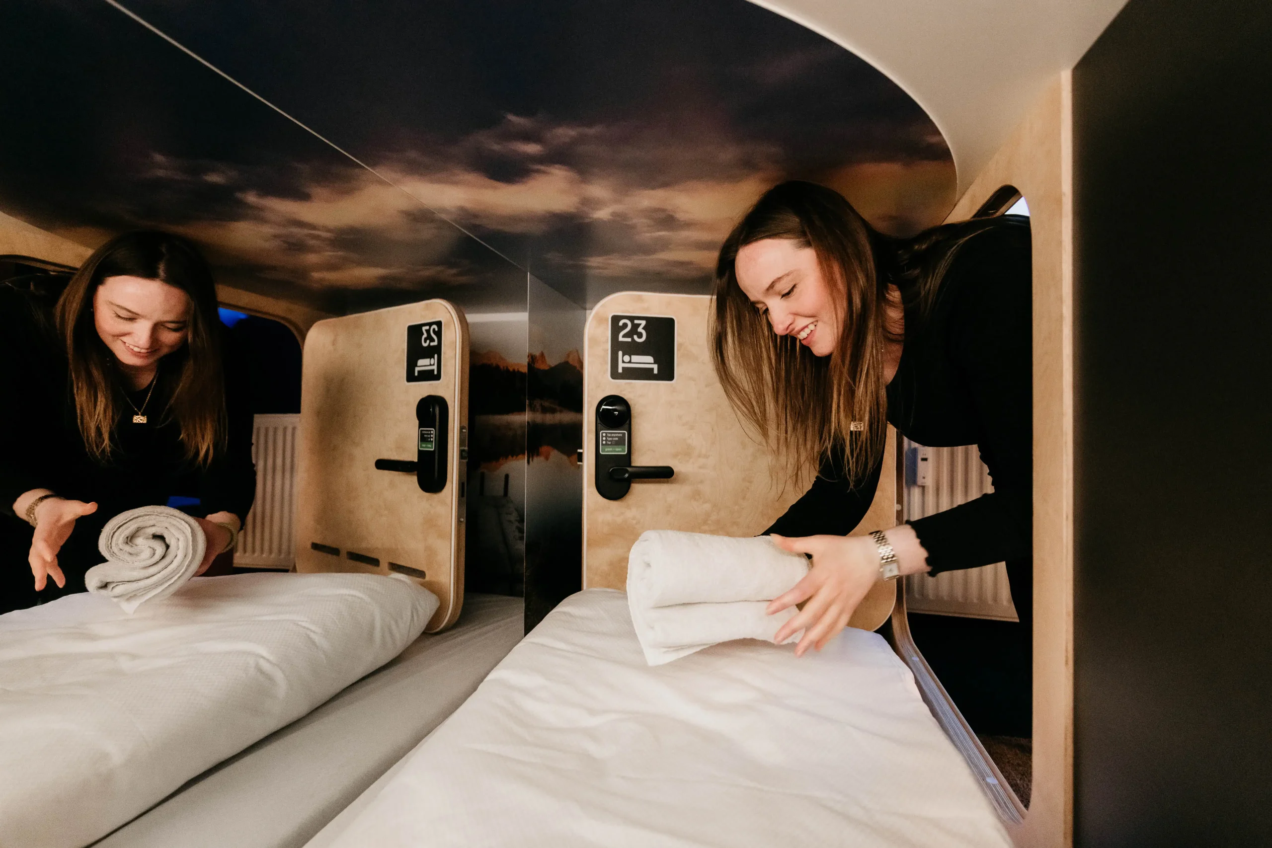 Preparing a capsule bed at Capsule Hotel Copenhagen Vesterbro, showcasing neat bedding and cozy capsule interior.