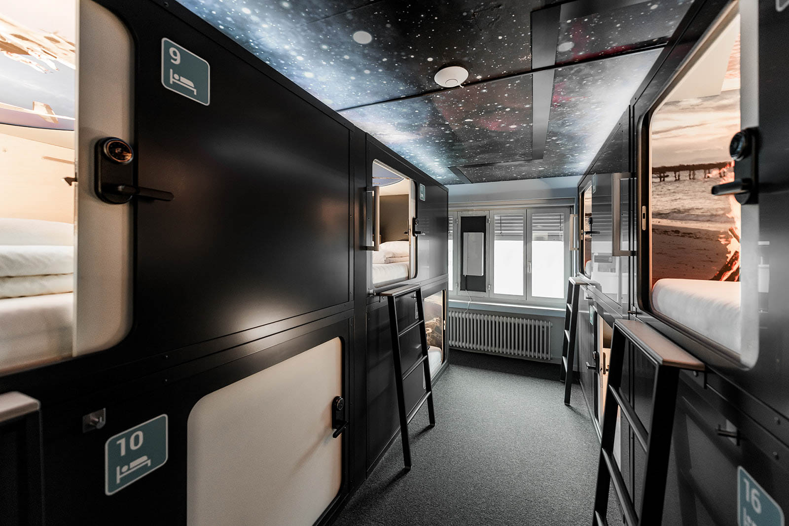 Space-themed capsule dorm with stacked sleeping pods and ladders at Capsule Hotel Lucerne The Lab.