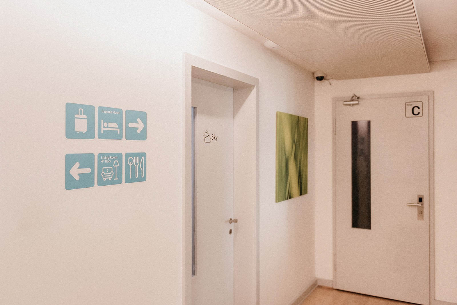 Corridor with directional signs and room doors, Capsule Hotel Lucerne The Lab.