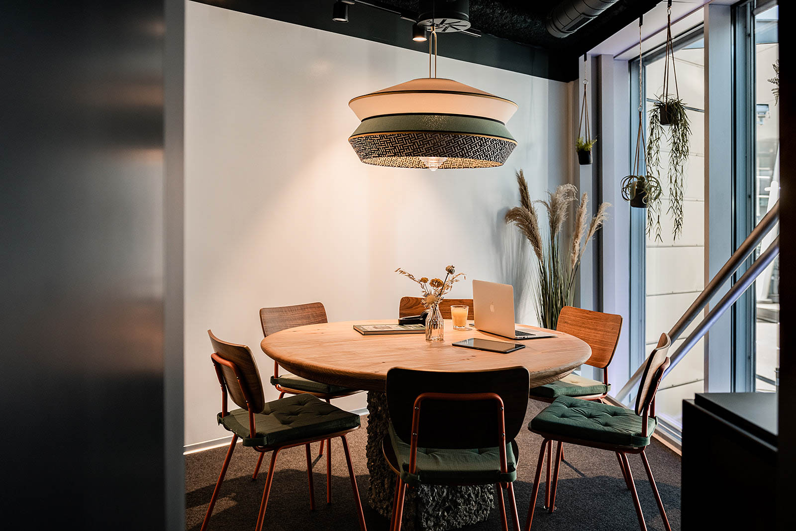 Stylish meeting area with round wooden table and chairs at Capsule Hotel Alpine Garden Zurich Airport.