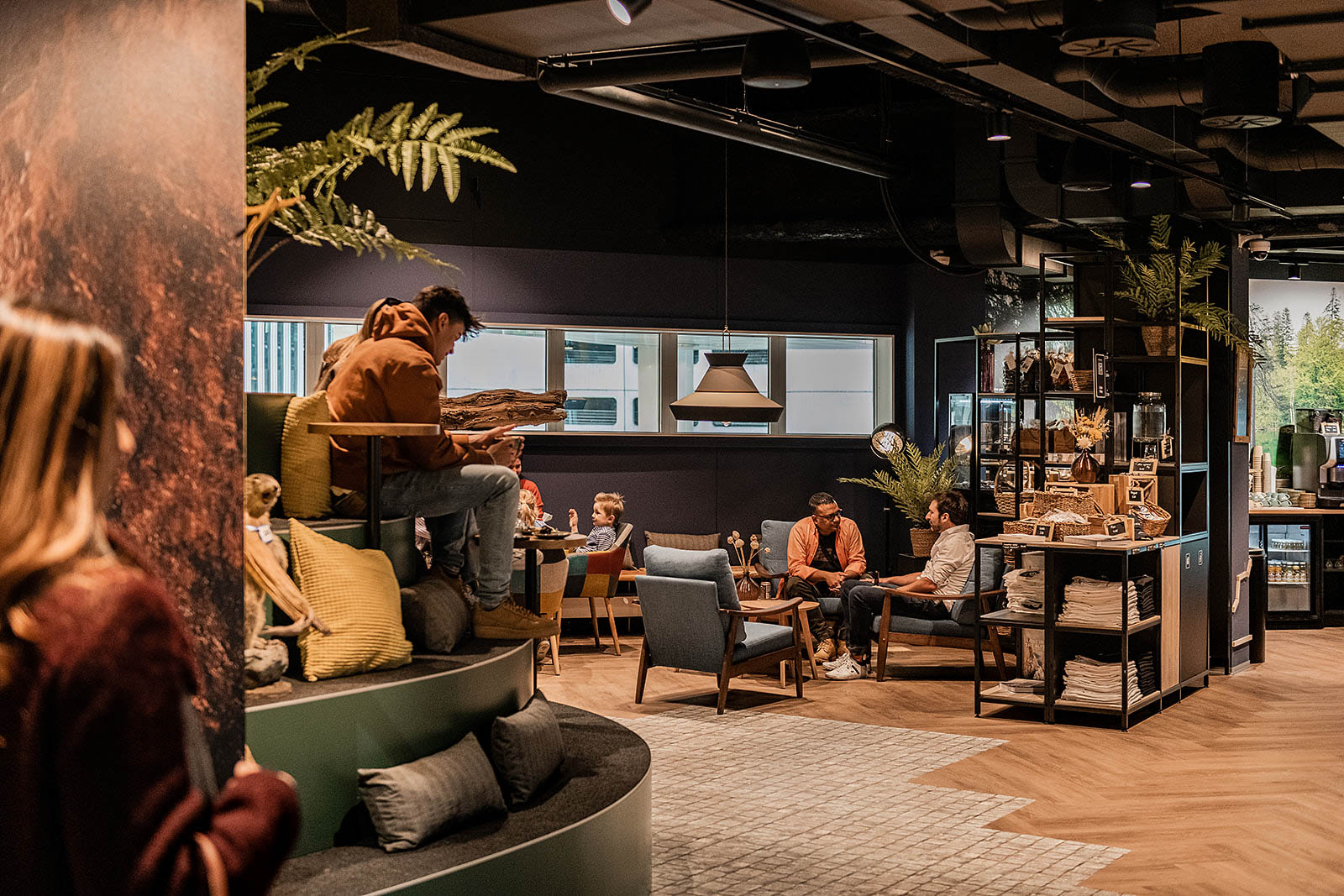 Eine gesellige Lounge, wo sich Gäste im Capsule Hotel Alpine Garden Zürich Flughafen entspannen und unterhalten.
