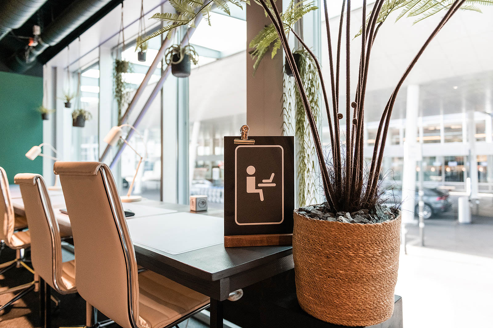 Cozy workspace with chairs, plants, and work sign at Capsule Hotel Alpine Garden Zurich Airport.