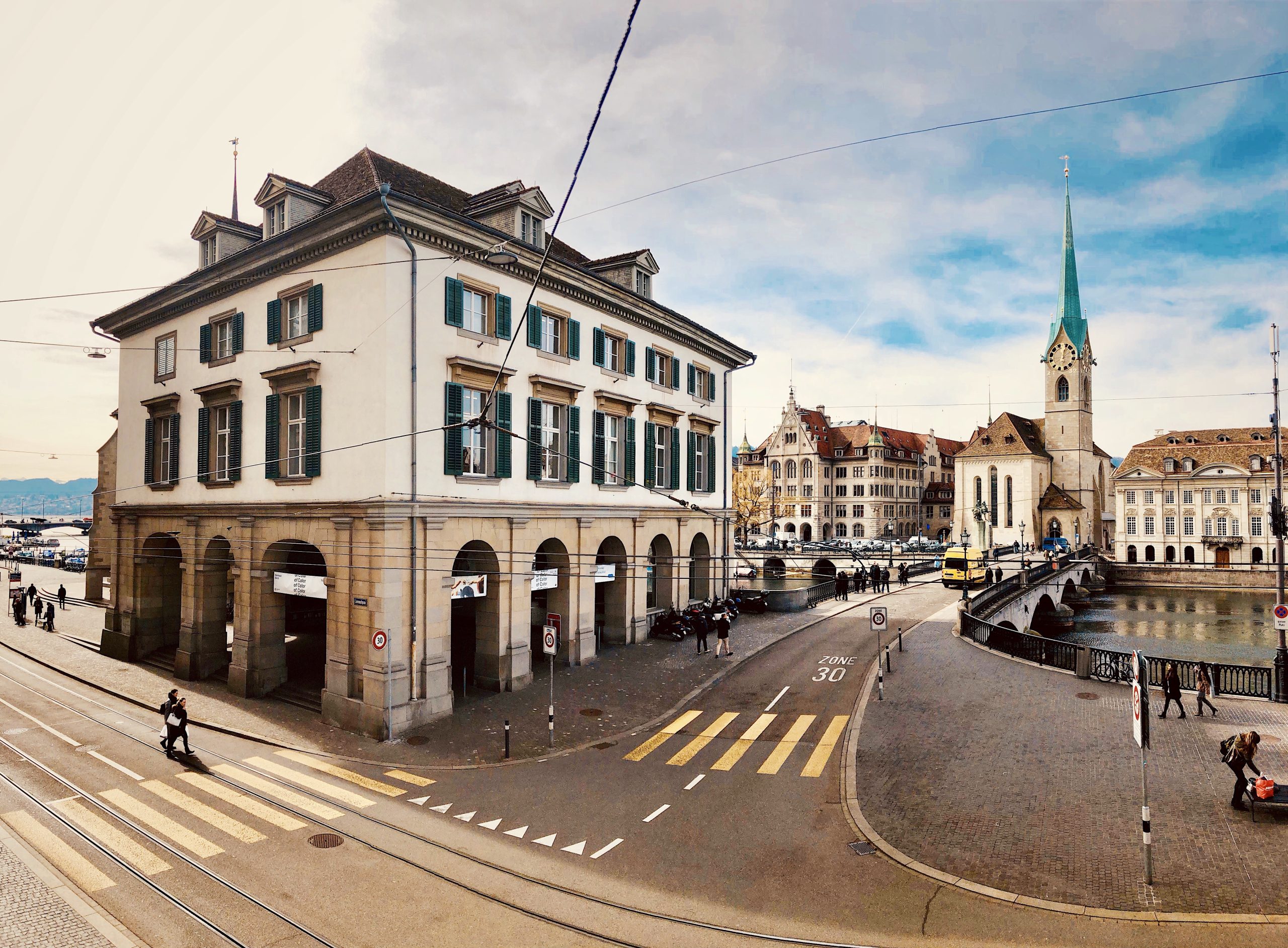 Strassenansicht in der Nähe des Capsule Hotels Alpine Garden Zürich Flughafen, mit einem historischen Gebäude und Flussufer.