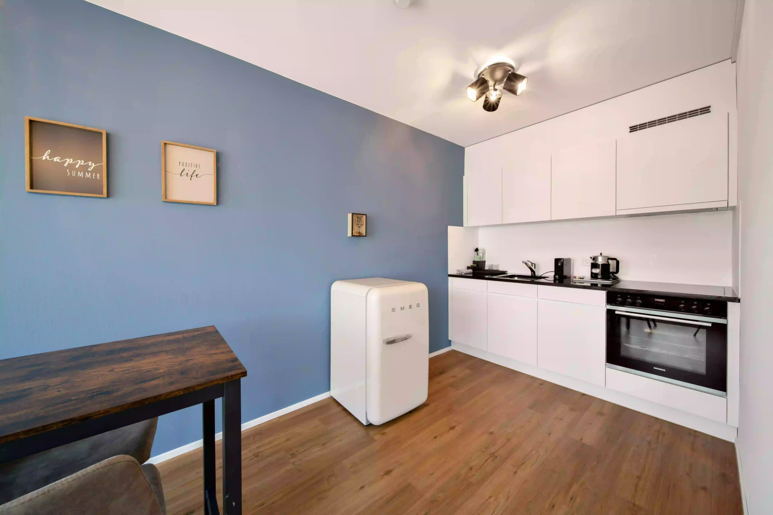 Kitchenette in private apartment with retro fridge and wooden table, Hyve Basel Capsule Hotel.
