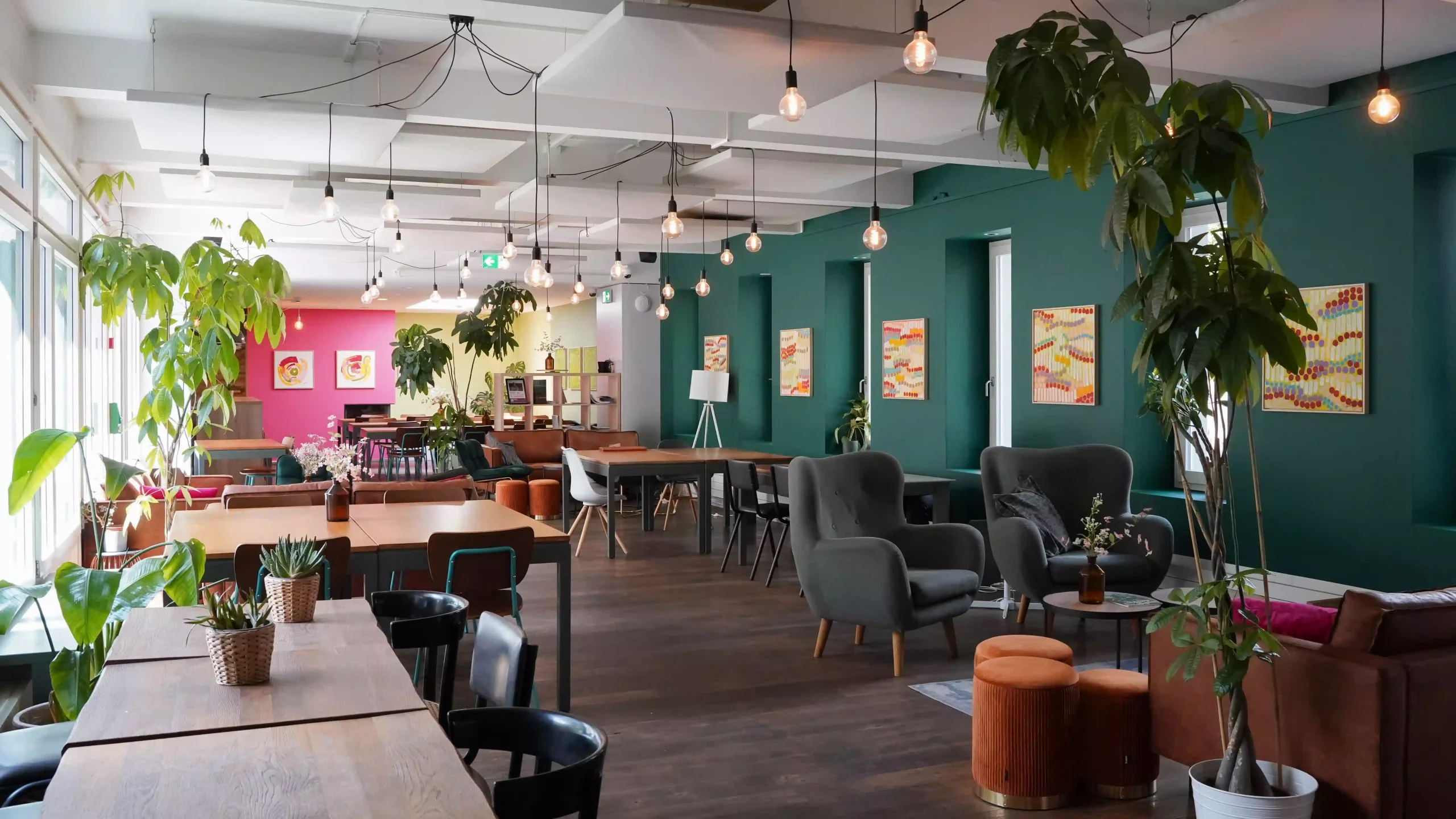 Lobby area with modern seating, potted plants, and colorful artwork at Hyve Basel Capsule Hotel.