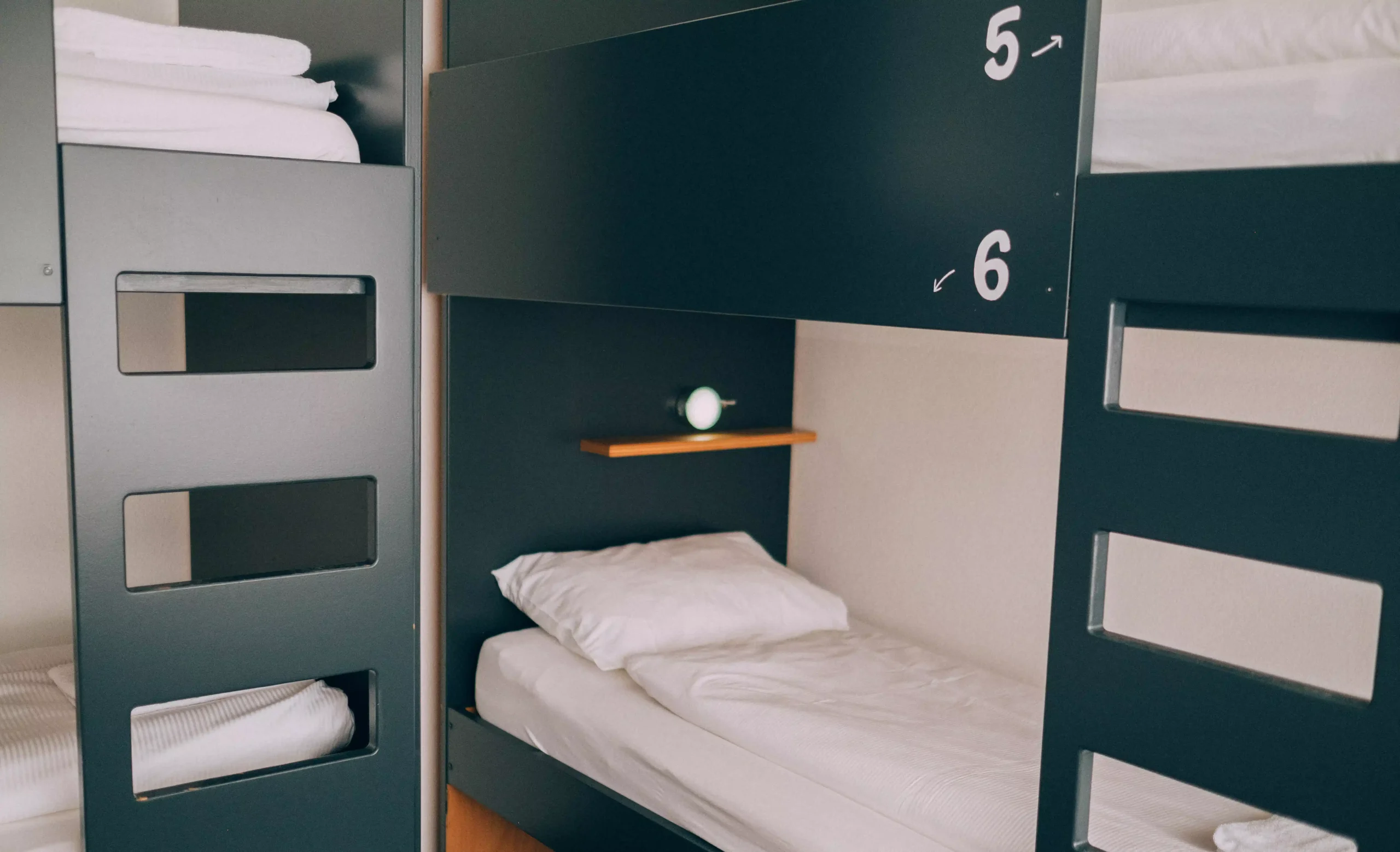 Bunk beds in a dorm room at Hyve Basel Capsule Hotel with numbered sections and soft lighting.