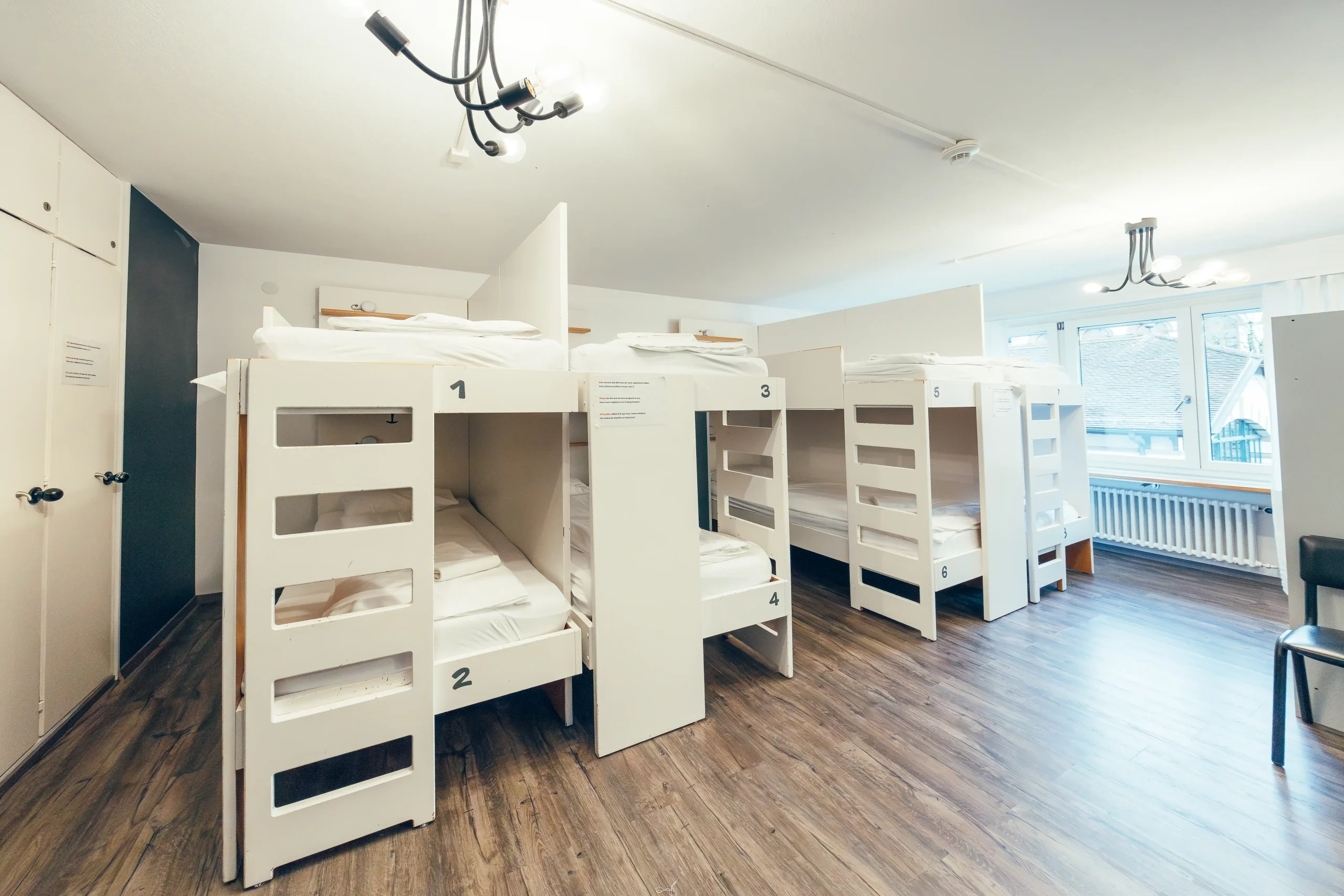 Dorm room with bunk beds and modern lighting at Hyve Basel Capsule Hotel.