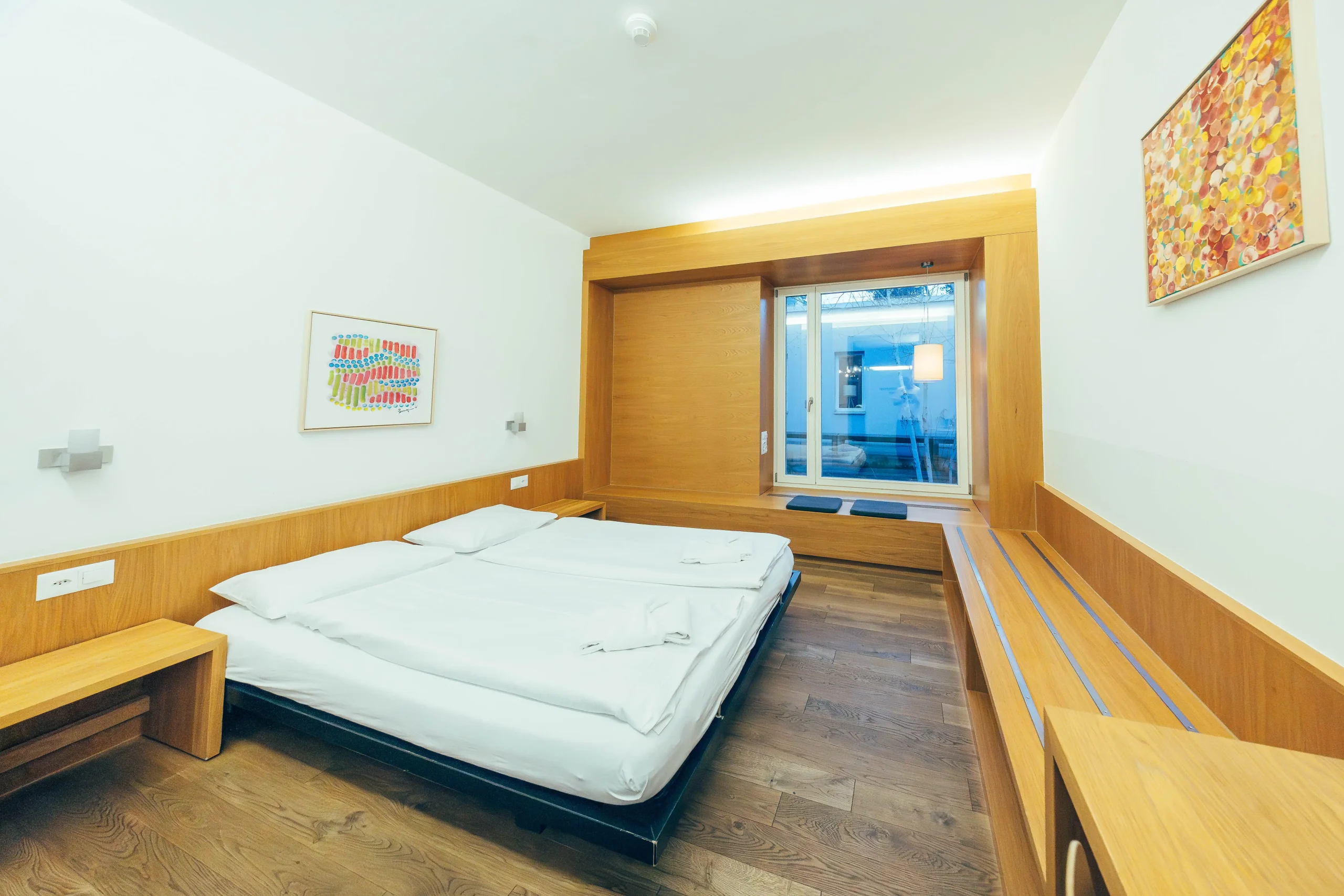 Bright private apartment with a double bed and modern artwork at Hyve Basel Capsule Hotel.