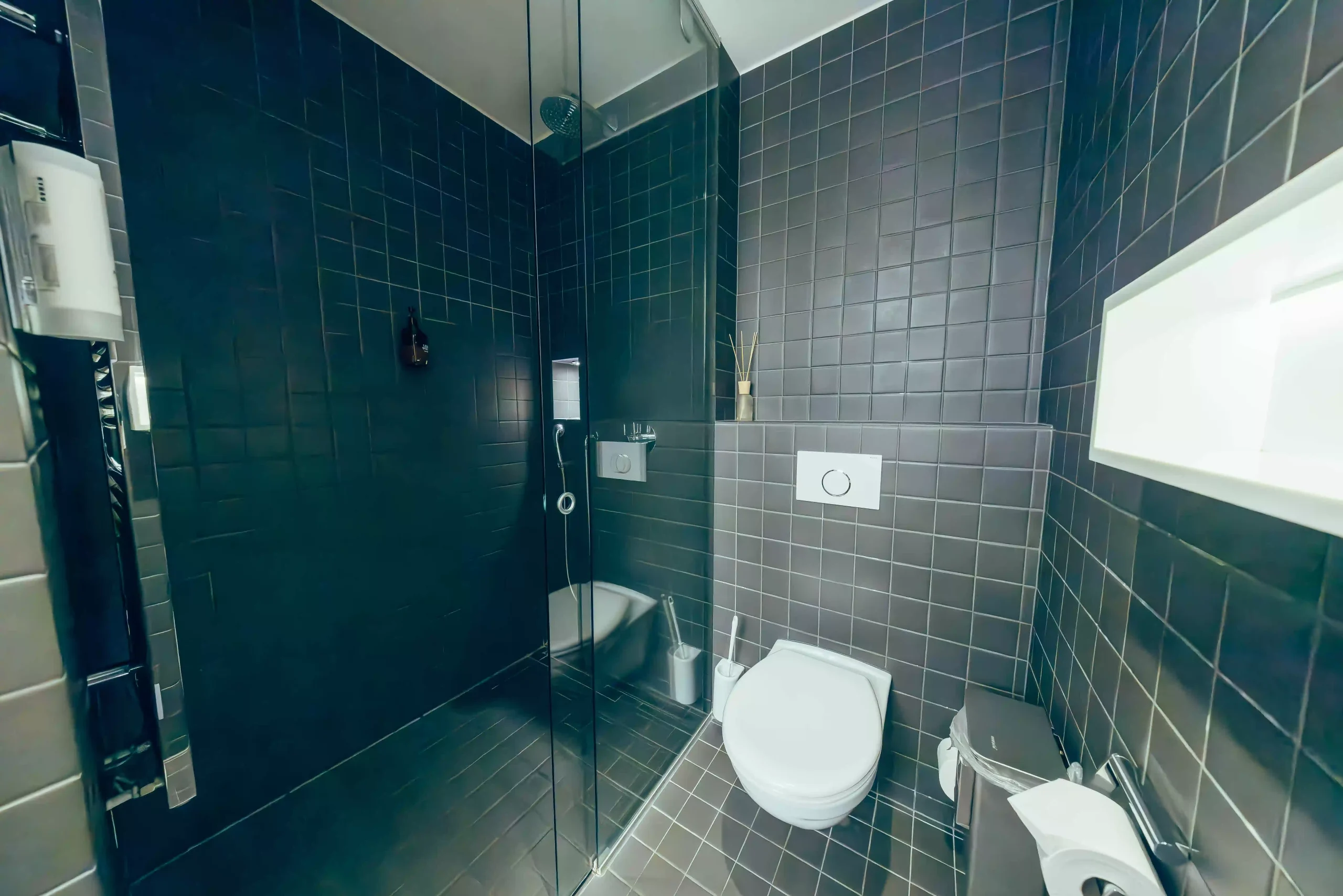 Modern bathroom with tiled walls and glass shower at Hyve Basel Capsule Hotel.
