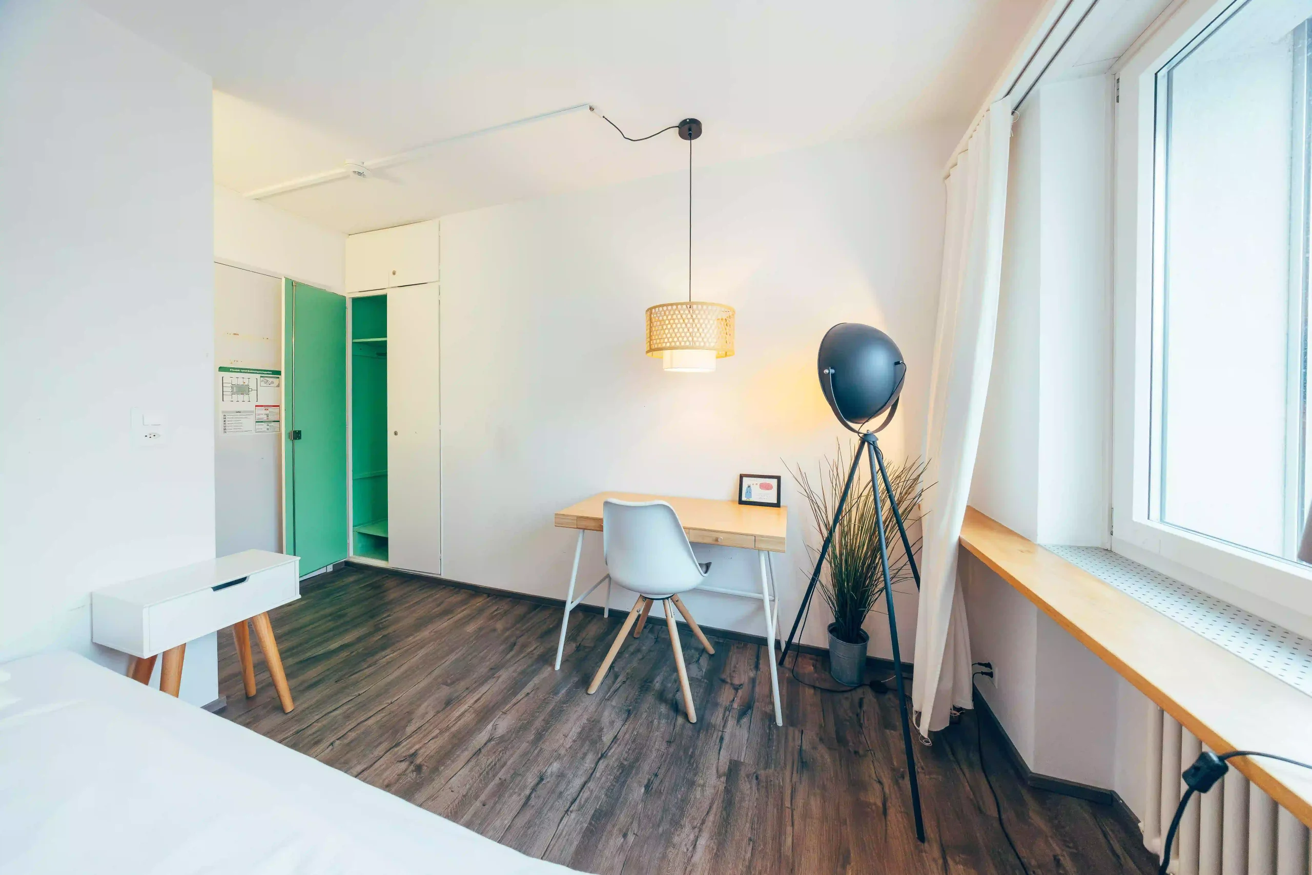 Modern apartment interior with desk, chair, lamp, and window at Hyve Basel Capsule Hotel.