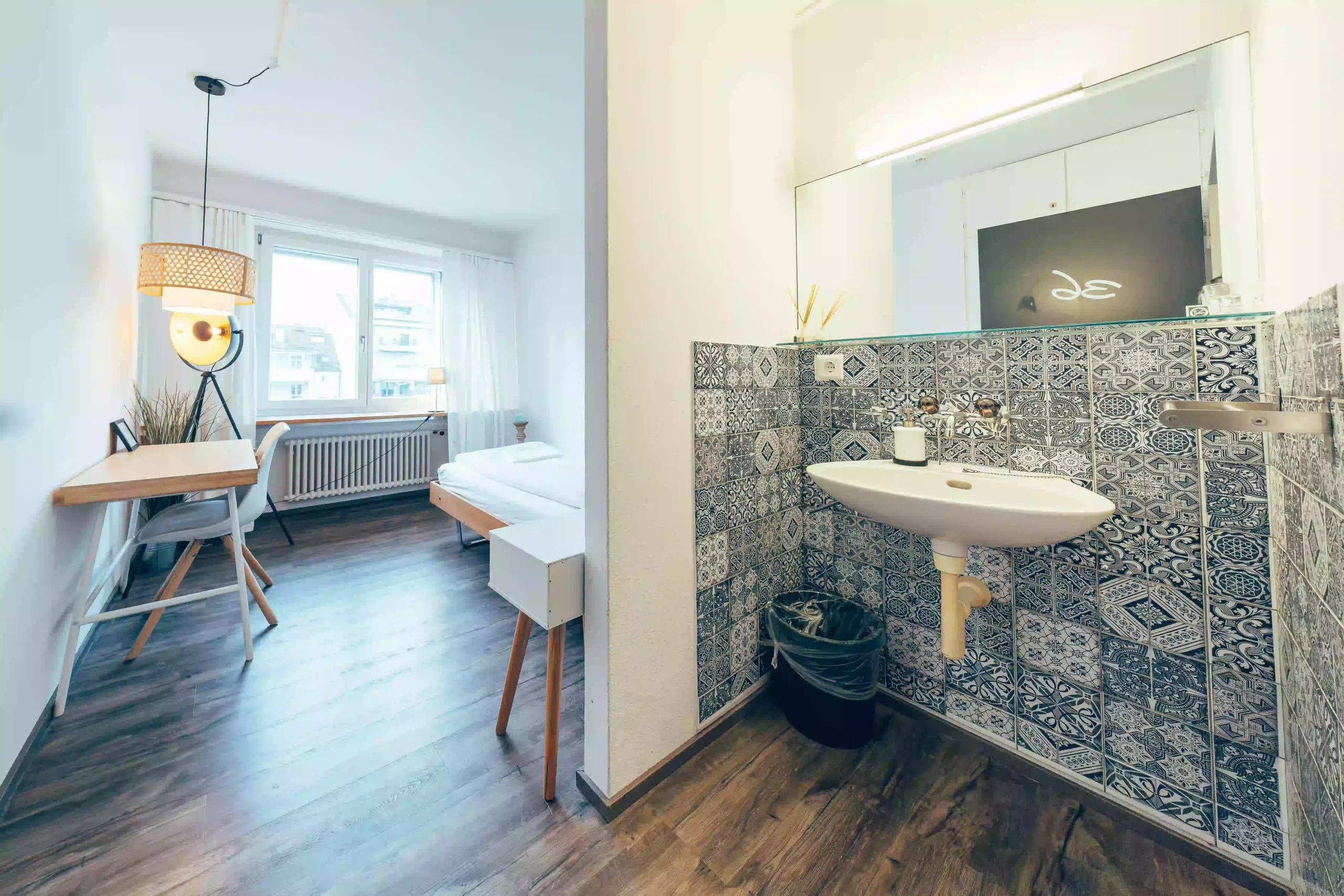 Modern private apartment with tiled sink area and cozy bedroom at Hyve Basel Capsule Hotel.
