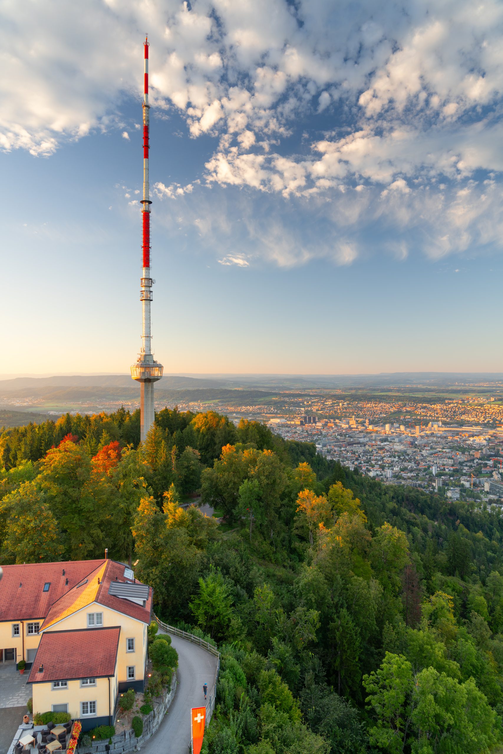 Luftaufnahme der Zürcher Stadtlandschaft mit üppigem Grün bei Sonnenuntergang in der Nähe des Capsule Hotel Alpine Garden Zürich Flughafen.