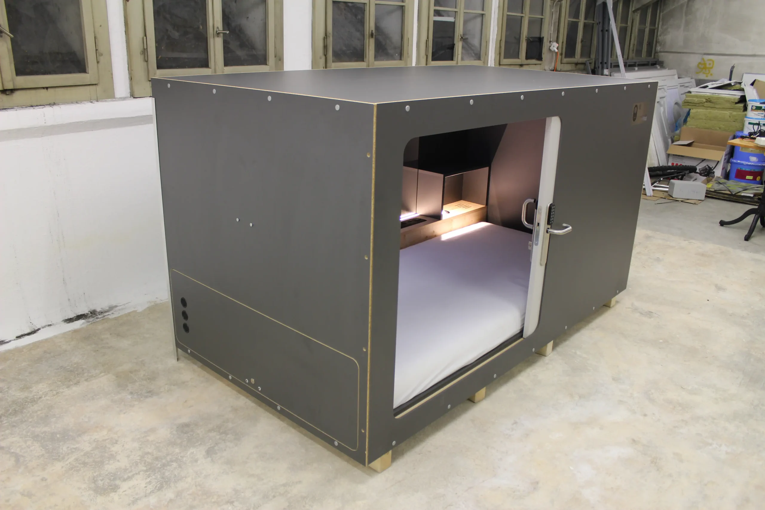 Stylish and modern sleeping pod at Capsule Hotel, featuring wood interior and clean bedding.