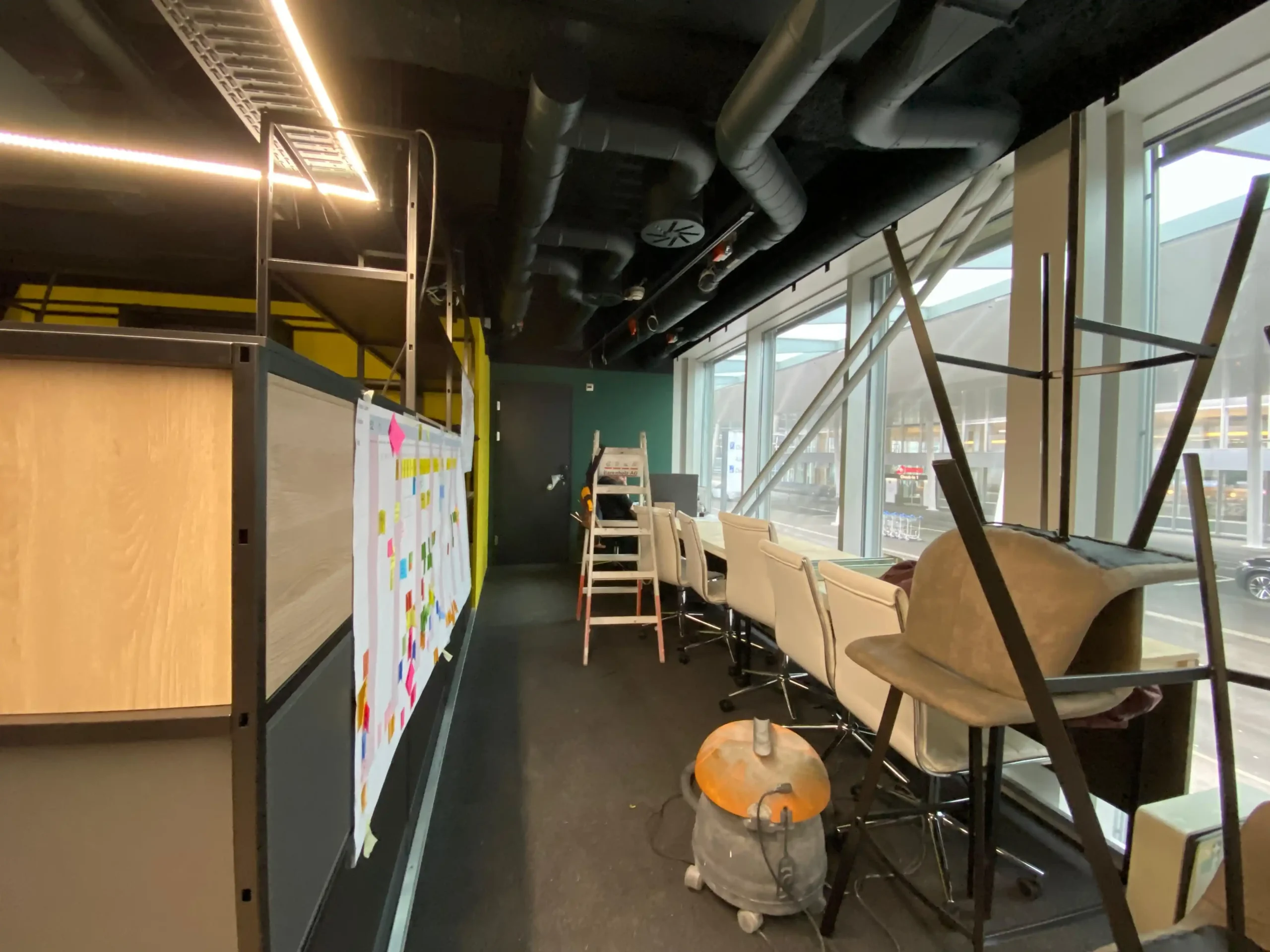 Modern workspace with post-it notes and chairs near large windows, showcasing Capsule Hotel's innovative design approach.