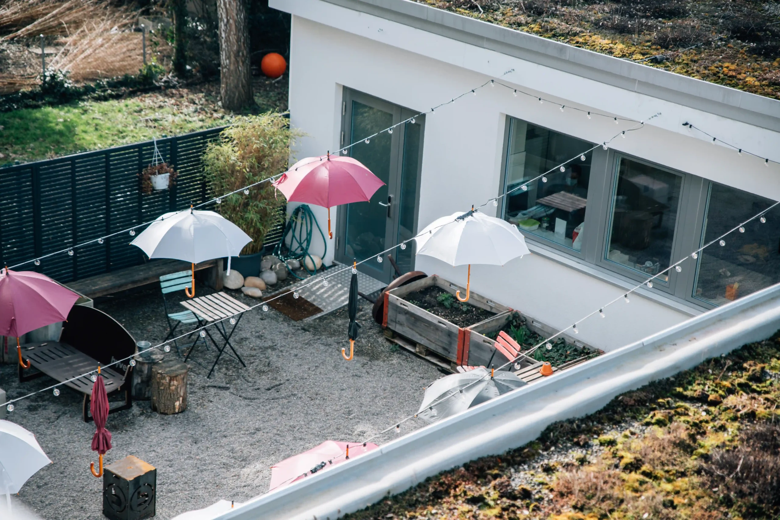 Courtyard at Capsule Hotel featuring colorful hanging umbrellas, seating, and greenery for a cozy outdoor atmosphere.