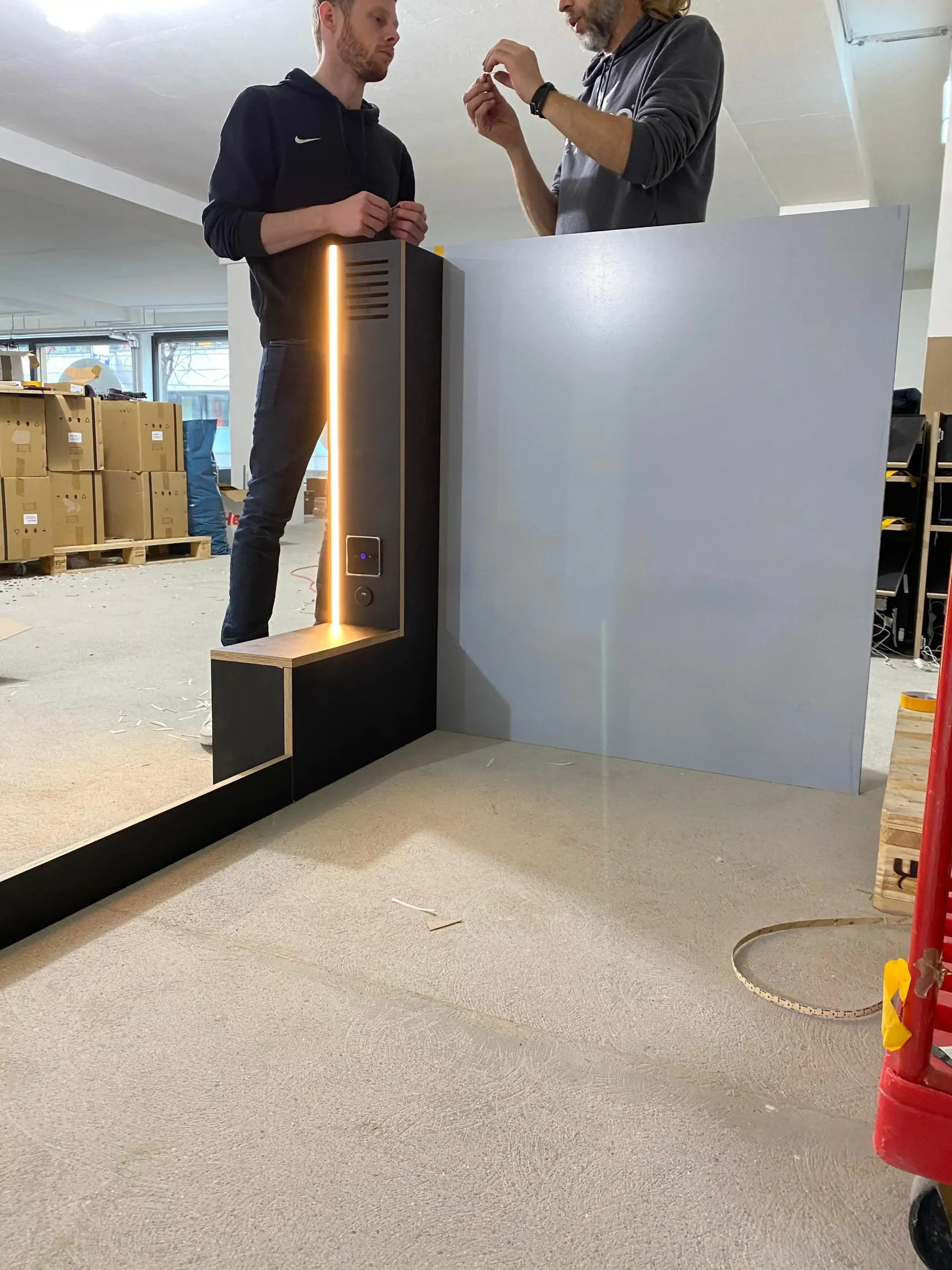 Technicians collaborating on capsule pod installation at Capsule Hotel workspace, showcasing innovative design development.