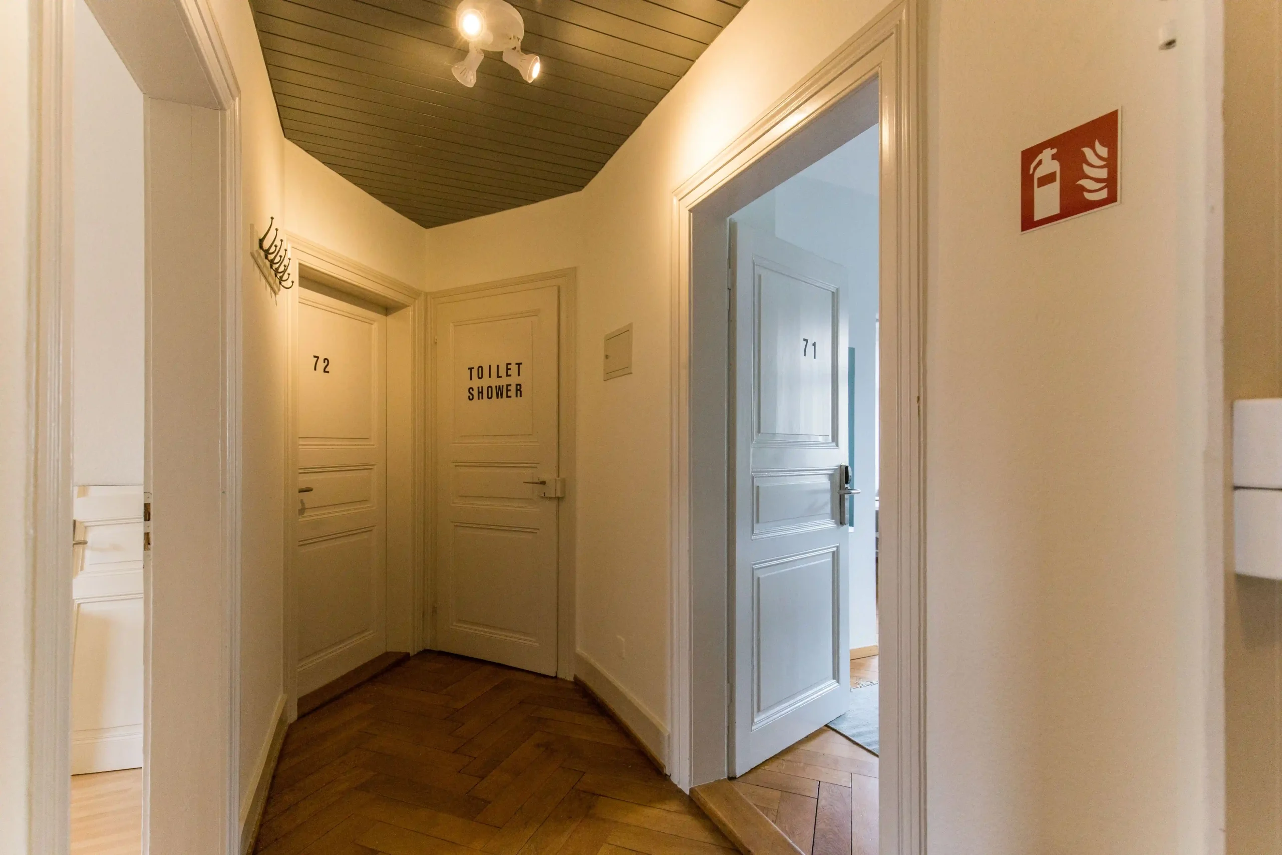 Hallway at Capsule Hotel with rooms 71, 72, and a toilet and shower. Stylish, minimalistic European design.