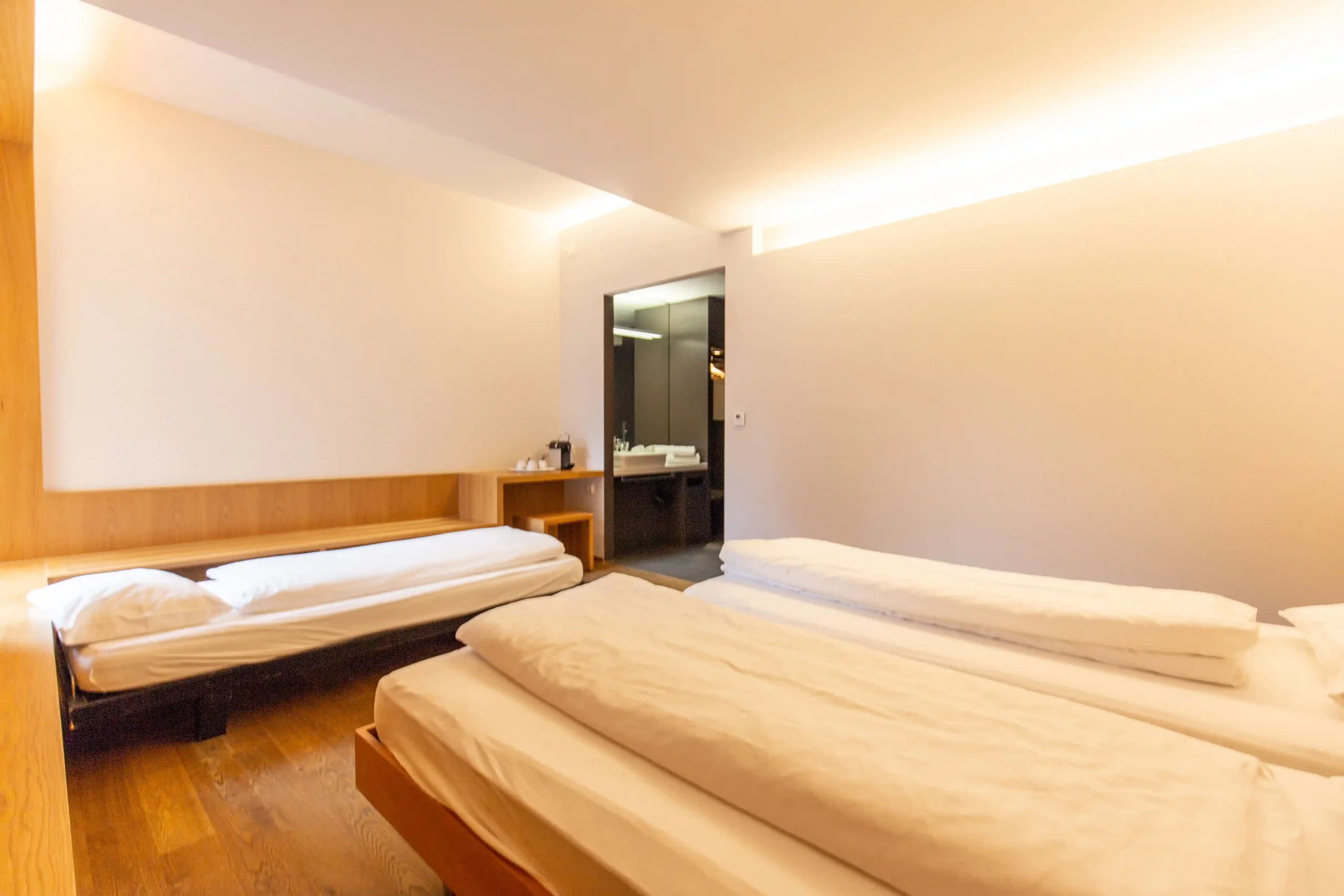 Minimalist Capsule Hotel room with sleek design, featuring two beds, wooden accents, and soft ambient lighting.