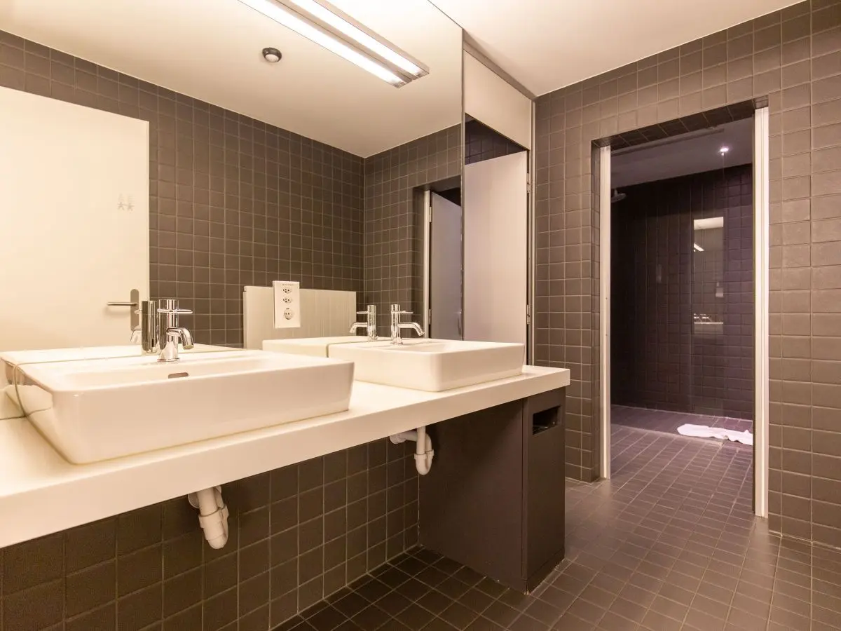 Modern, sleek bathroom with dual sinks and gray tiles at Capsule Hotel.
