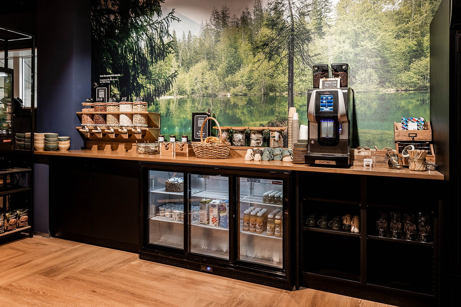 Snack and beverage station with coffee machine and natural decor at Capsule Hotel Alpine Garden Zurich Airport.