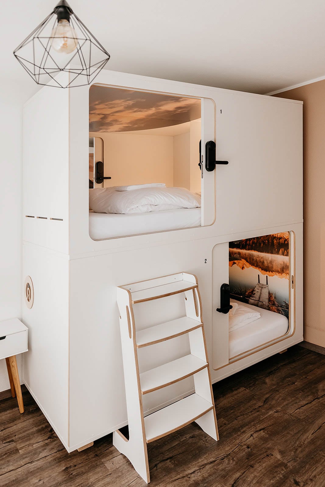 Stair-accessed double capsule room with cozy bedding at Hyve Basel Capsule Hotel.