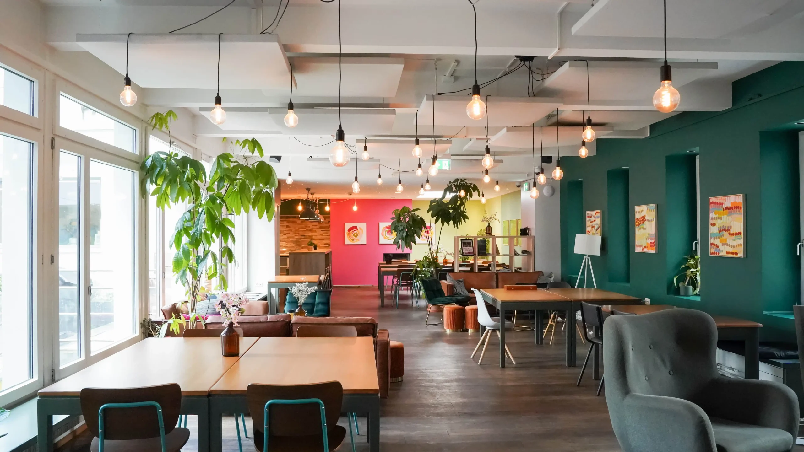 Modern, vibrant lounge area with greenery and eclectic seating at Hyve Basel Capsule Hotel.
