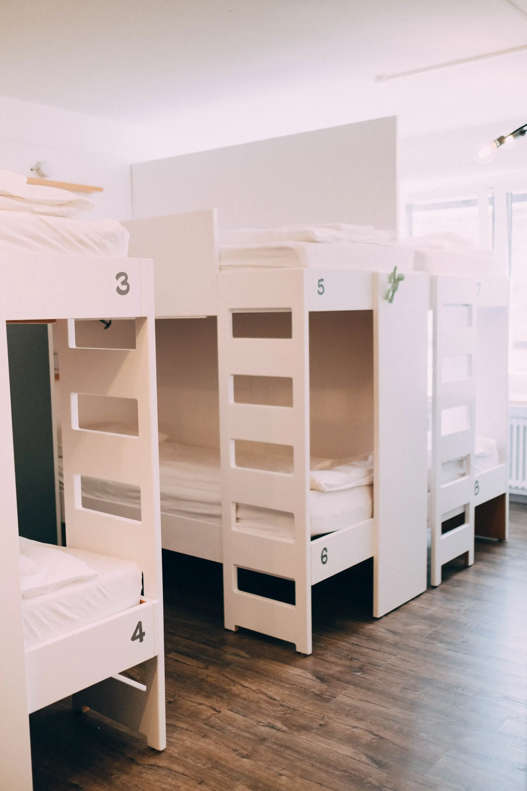 Modern dormitory with white bunk beds at Hyve Basel Capsule Hotel.