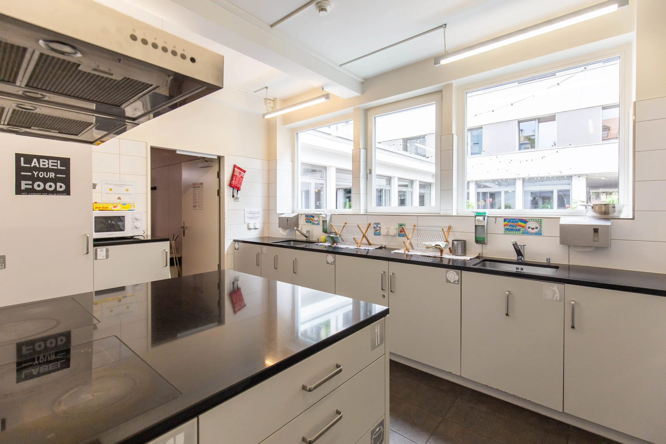 Modern communal kitchen with large counters at Hyve Basel Capsule Hotel.